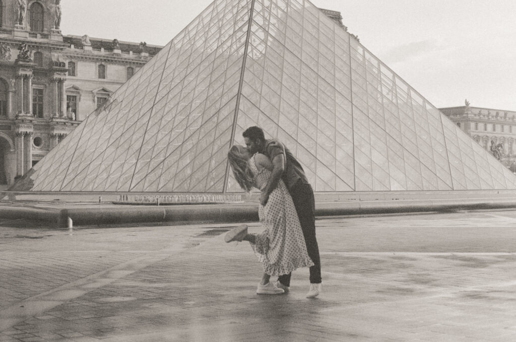 A couple kisses in front of the Louvre, a beautiful backdrop for a Paris elopement.