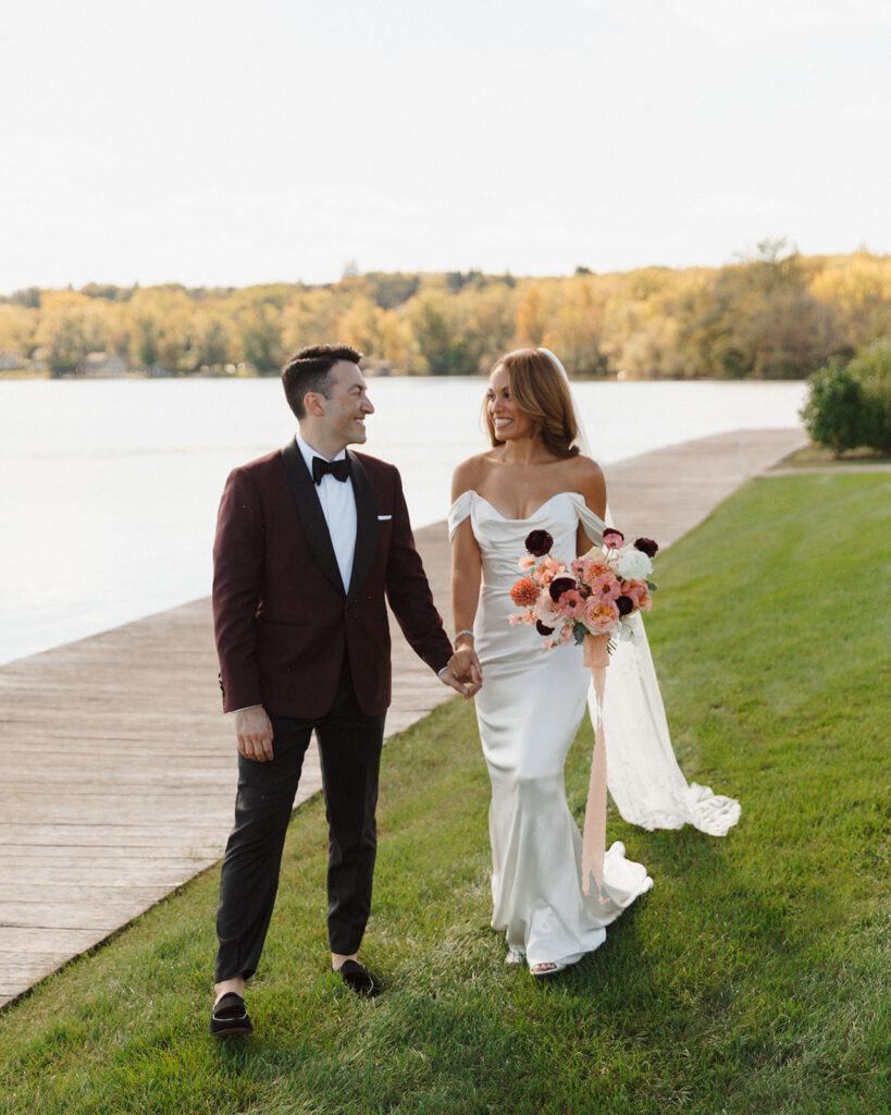 A couple walks the grounds of The Lake House on Canandaigua for their fall wedding in the Finger Lakes.