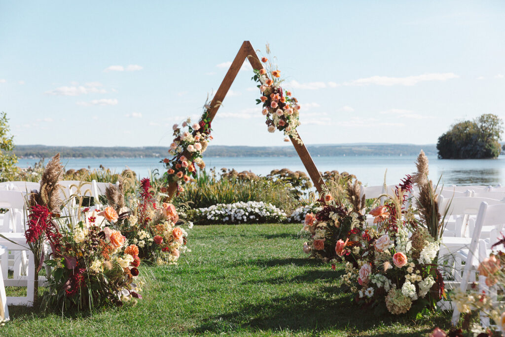 Floral meadows line the aisle with grasses and peachy pink flowers for a fall wedding at the Lake House on Canandaigua