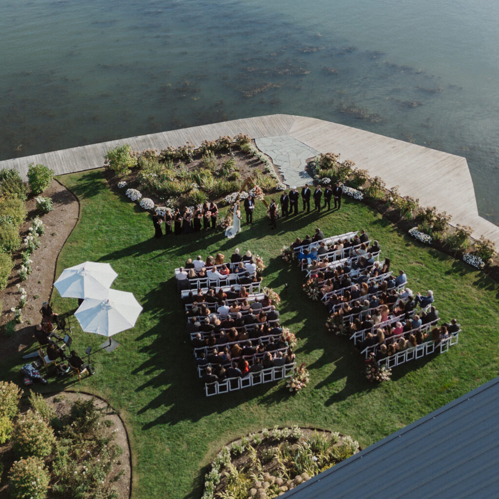 An aerial view of a wedding at The Lake House on Canandaigua, the ceremony overlooking the beautiful vast blue lake in the Finger Lakes.