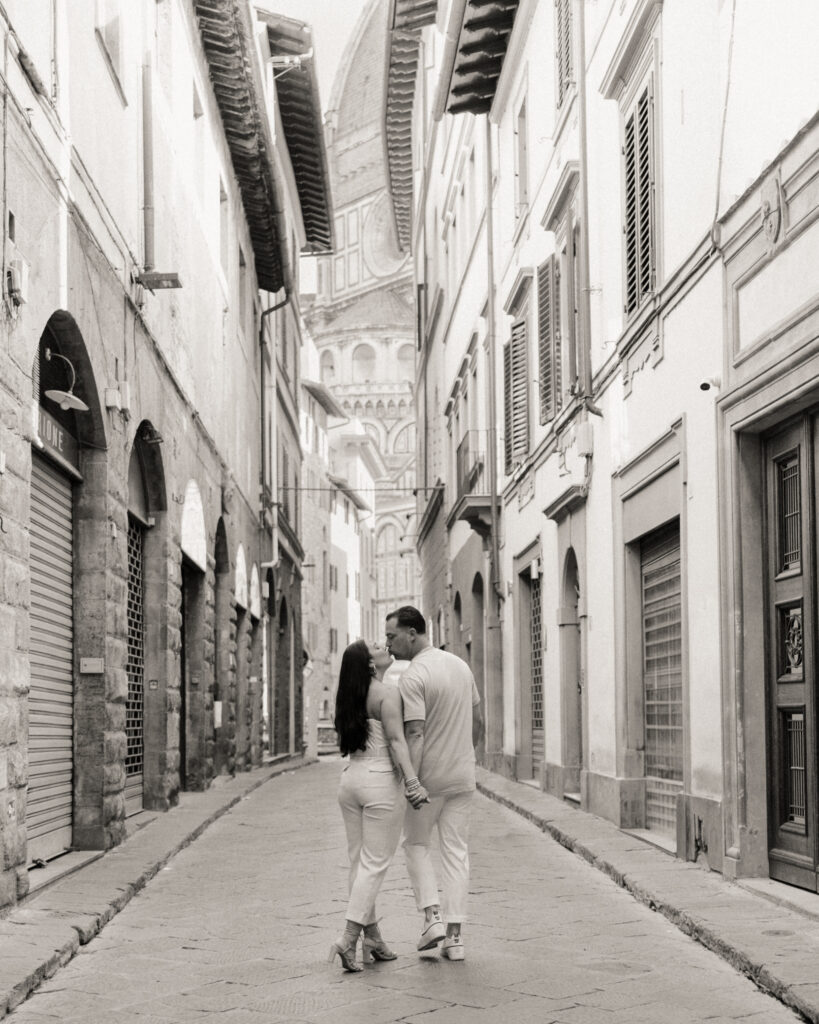 A couple in the streets of Florence, Italy for their engagement session, with the Duomo behind them.