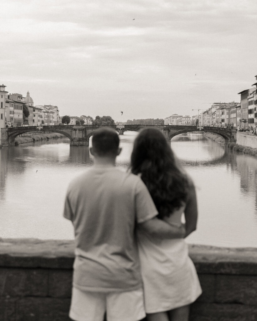 A couple watches the sun rise at Ponte Vecchio in the city of Florence for their engagement session.